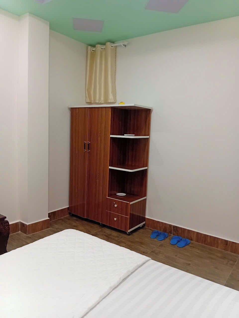 Ein Schlafzimmer mit einem Holzschrank, einem Bett und einem Paar blauer Hausschuhe auf dem Boden.