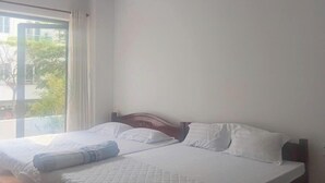 A bedroom with a large bed, a window with curtains, and a view of greenery outside. - MOTEL DONG KHOI (Phu Tan)