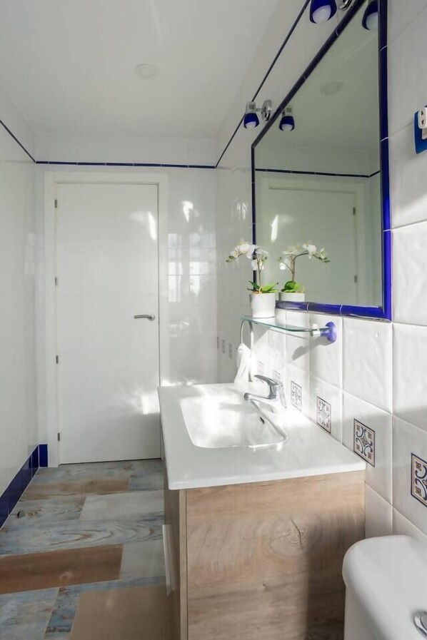 A modern bathroom with a white sink, wooden vanity, and a large mirror with a blue frame.