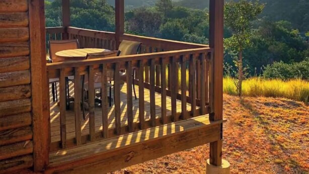 A wooden cabin with a porch overlooking a mountainous landscape.