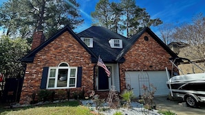 A two-story brick house with a garage, a lawn, and a boat in the driveway. - Masters week with Hot Tub (Martinez)