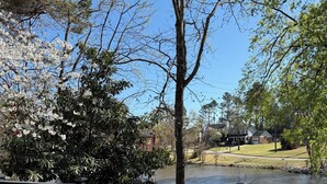 A wooden deck with a view of a lake, surrounded by trees and a residential area. - Masters week with Hot Tub (Martinez)