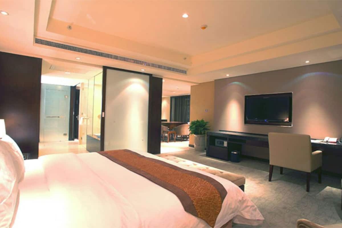 Ein Hotelzimmer mit einem großen Bett, einem Schreibtisch mit Computer, einem Fernseher und einer Sitzecke.