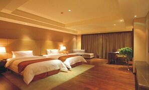 Una camera d'albergo con due letti, un divano, una scrivania e una pianta.