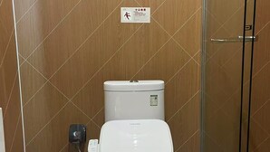 A modern bathroom with a toilet, a trash bin, and a glass shower enclosure. - Piaohome Chain Hotel (Beijing)
