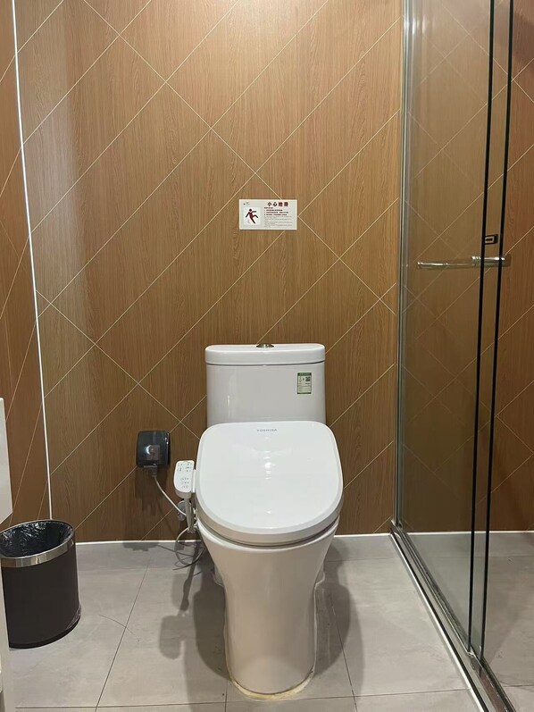 A modern bathroom with a toilet, a trash bin, and a glass shower enclosure. - Piaohome Chain Hotel (Beijing)