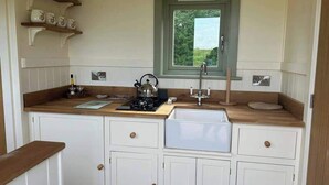 Una cucina compatta con mobili bianchi, un piano di lavoro in legno, una finestra con vista e un lavello integrato.