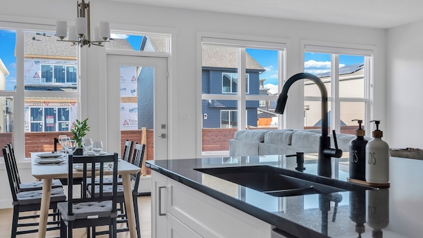 A modern kitchen with a large island, a dining area with a table and chairs, and large windows offering views of neighboring houses. - Luxury 3BDR large House-4 mins to Seton Hospital-Parking / Pet Free  (Calgary)