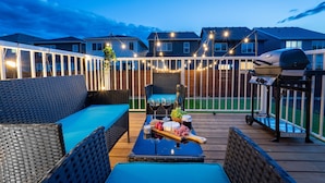An outdoor deck with wicker furniture, a grill, and a table with food and drinks. - Luxury 3BDR large House-4 mins to Seton Hospital-Parking / Pet Free  (Calgary)