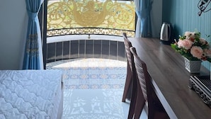 A room with a balcony, a bed, a desk, a chair, and a TV. - Kim Ngan Motel (Chau Doc)