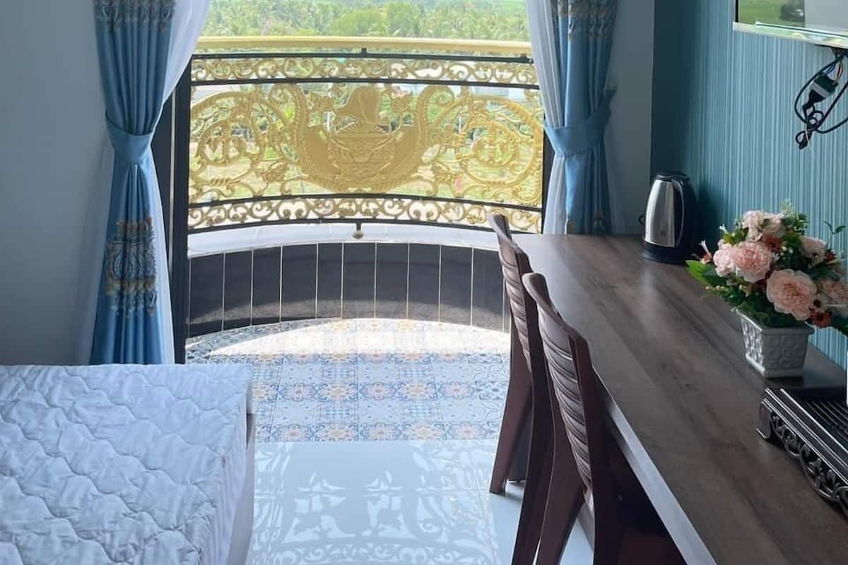 Una habitación con balcón, cama, escritorio, silla y televisión.