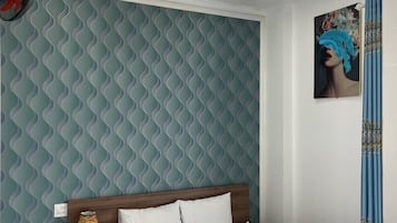 A bedroom with a patterned wallpaper, a wooden headboard, a white bedspread, a bedside table with a lamp, and a ceiling fan.