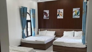 A modern bedroom with three beds, wooden paneling on the walls, and artwork. - Kim Ngan Motel (Chau Doc)