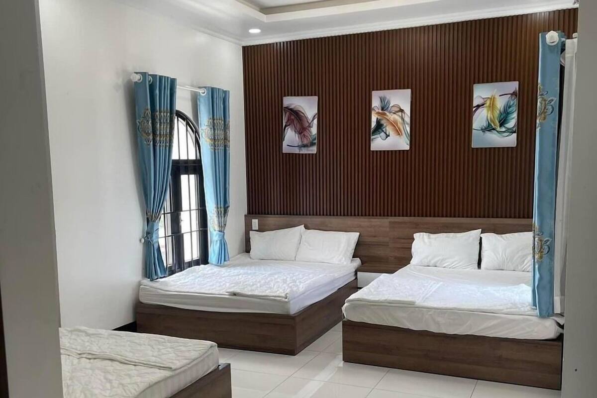 Un dormitorio moderno con tres camas, paneles de madera en las paredes y obras de arte.