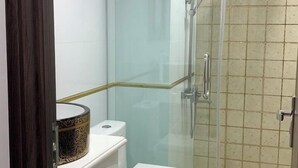 A bathroom with a glass-enclosed shower, a white toilet, and a sink with a decorative basin. - Kim Ngan Motel (Chau Doc)