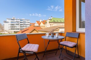 Un balcon avec deux chaises et une petite table, donnant sur un quartier résidentiel composé de différents immeubles.