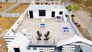 An aerial view of a rooftop with a small building, outdoor seating area, and a fenced perimeter. - Paradise Point Resort (Jaipur)