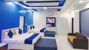 A hotel room with a modern design, featuring a large bed, a sofa, a TV, and a ceiling fan. - Paradise Point Resort (Jaipur)