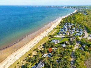 An aerial view of a coastal residential area with houses along the beach, a clear view of the ocean, and a marked location on the map. - Beachfront, Just steps and you're on the beach! (Saco)