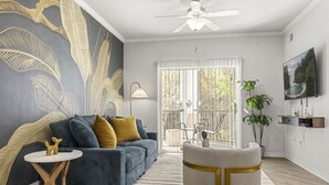 Una sala de estar moderna con un sofá azul, una mesa de centro redonda y un mural grande en la pared.