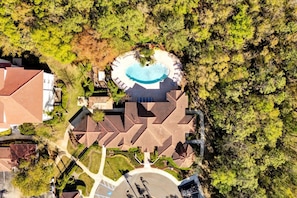 An aerial view of a resort with a swimming pool, a parking area, and a landscaped garden.