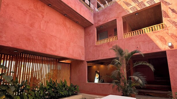Un atrium à plusieurs niveaux doté d’une piscine, d’un espace détente avec un canapé et offrant une vue sur le ciel à travers des motifs ajourés sur les murs.