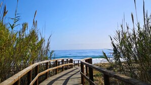 A wooden boardwalk leading to a beach with clear skies. - 501 Mirasol eme by Maison El Ático (Arenales Del Sol, Los)