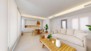 A modern living room with a sofa, a dining table, and a kitchen in the background. - 501 Mirasol eme by Maison El Ático (Arenales Del Sol, Los)