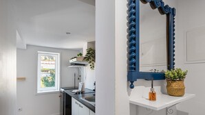 Una cocina moderna con ventana, estufa integrada y un espejo con marco azul.
