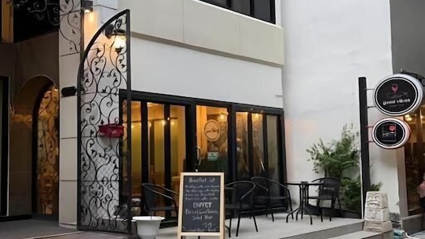 Un restaurante con terraza, una cartelera y una escalera que lleva a la entrada.