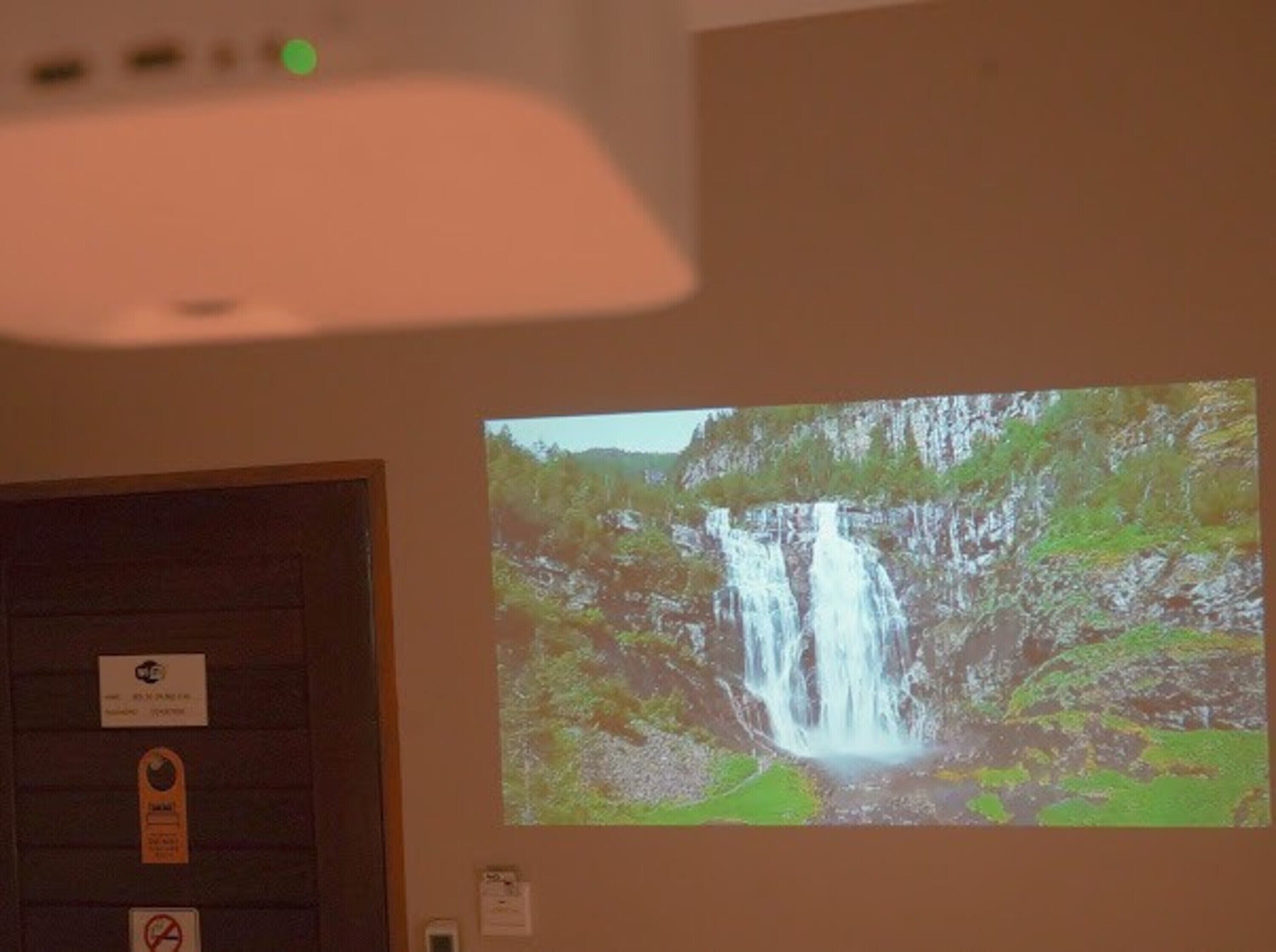 Proyección de una cascada en una pared, con una puerta y un letrero encima.