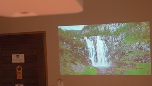 Proyección de una cascada en una pared, con una puerta y un letrero encima.