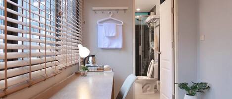 Une salle de bain moderne avec une douche, une serviette accrochée au mur et une petite plante.