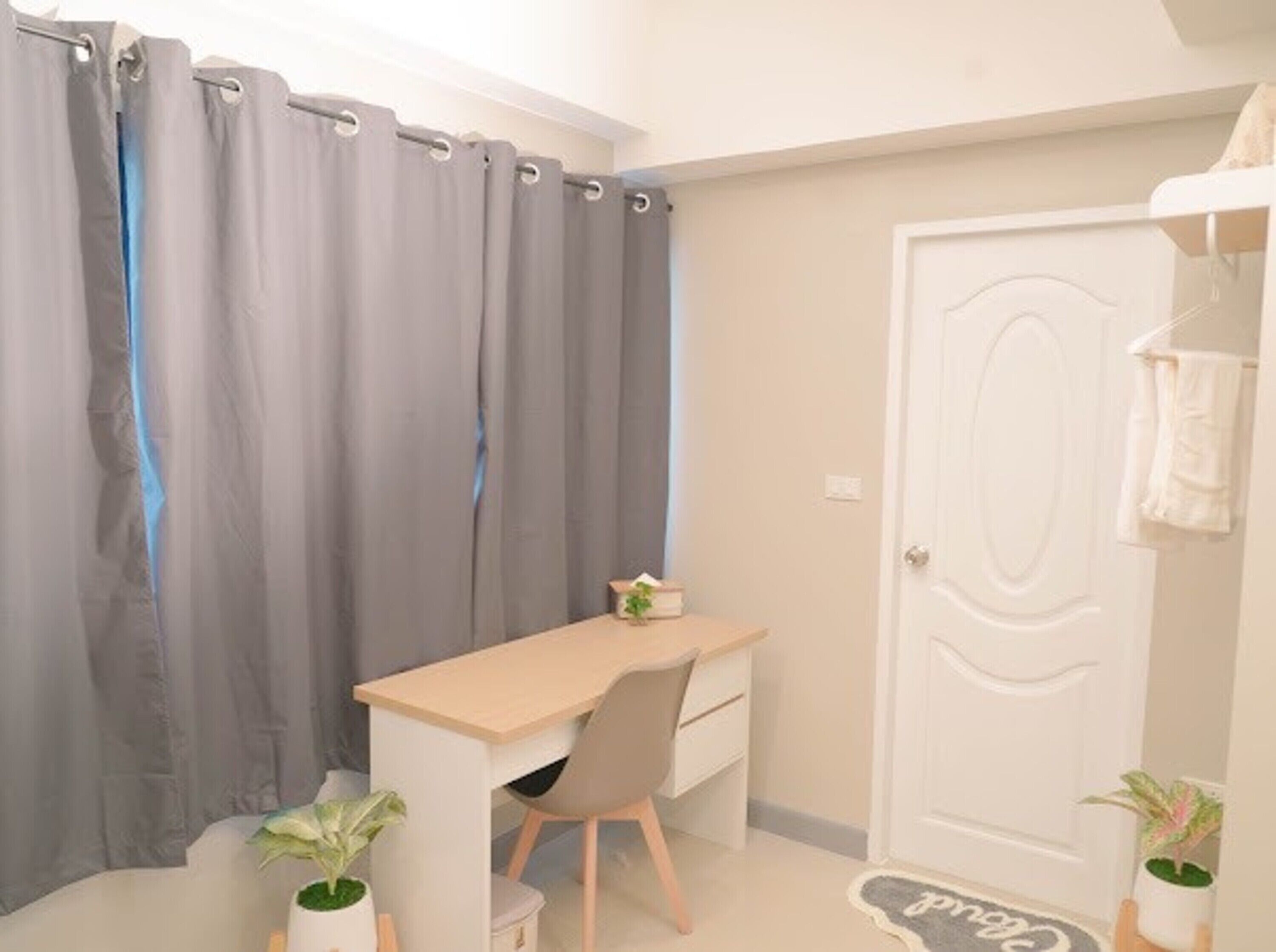 Une petite pièce, bien rangée, avec un bureau, une chaise et deux plantes en pot.