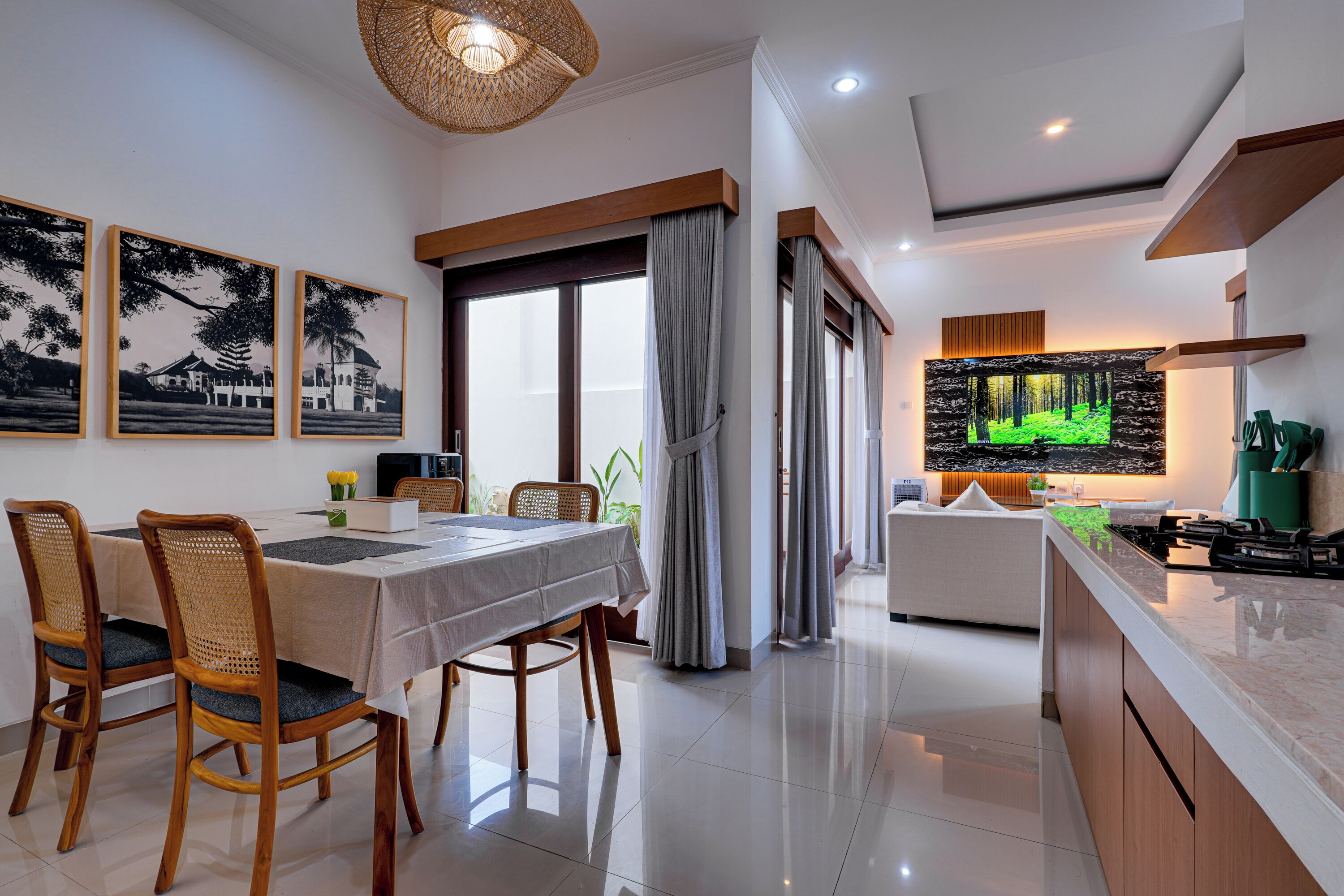 A modern dining area with a table set for four, wooden chairs, and a large window with curtains.