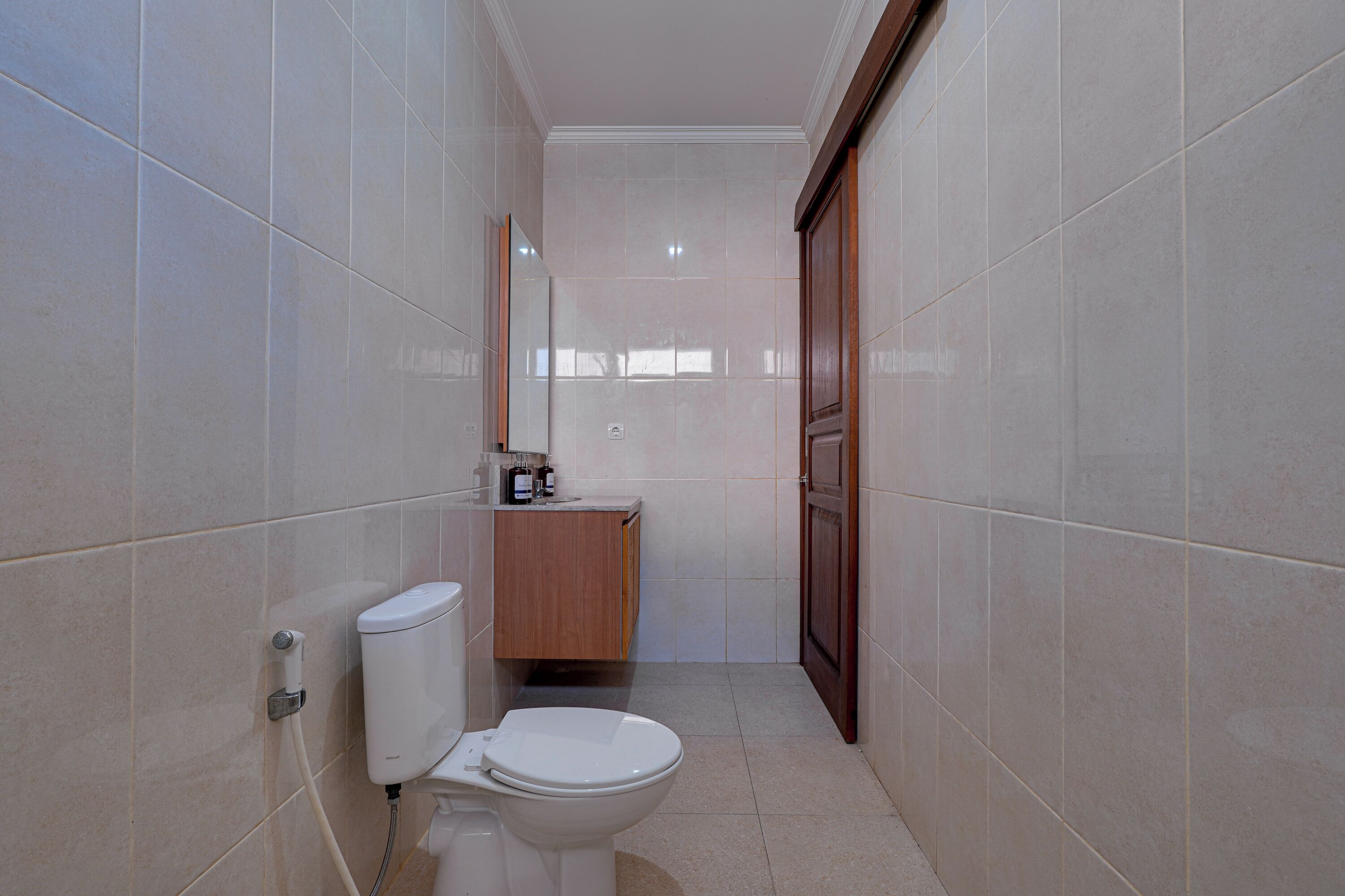 A small, narrow bathroom with a toilet, sink, and cabinet.