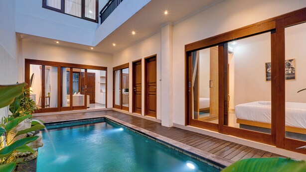 A modern hotel interior with a swimming pool, wooden doors, and a balcony. - Villa Boswelia Seminyak (Seminyak)