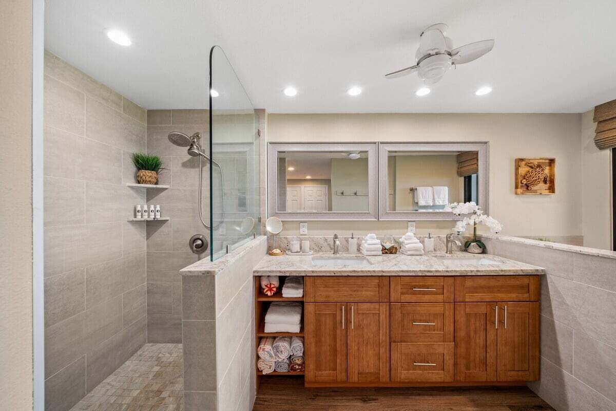 Ein modernes Badezimmer mit Dusche, Waschbecken und Deckenventilator.