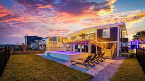 Una casa moderna con piscina, mobiliario de exterior y una escalera.