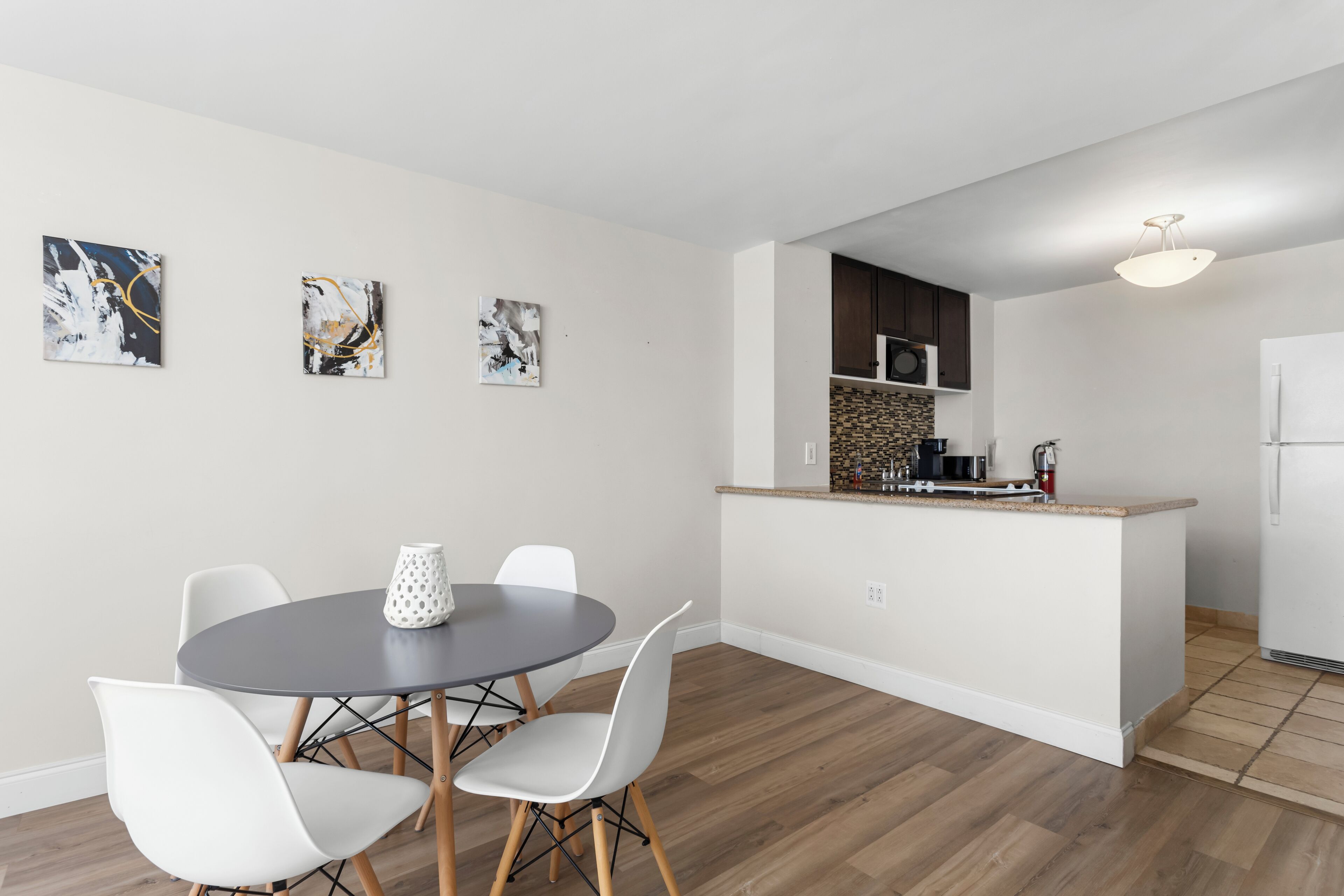A modern kitchen with a central island, white cabinetry, and a built-in microwave.