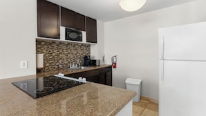 A modern kitchen with dark cabinets, a microwave, a built-in oven, a sink, and a white refrigerator. - Bay Harbor Sunset Apt 3B (Bay Harbor Islands)
