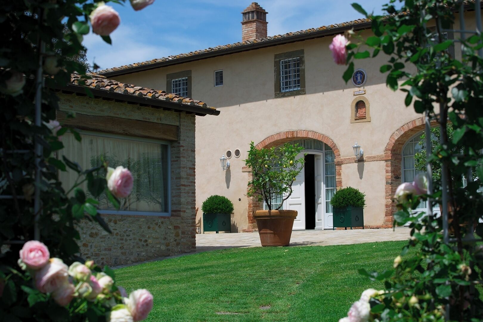 A building with a stone facade, arched doorways, and a well-maintained lawn.