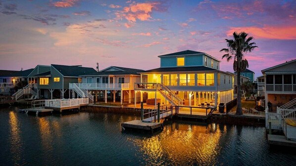 A waterfront property with multiple houses connected by walkways, a dock, and a palm tree.
