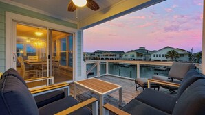 A balcony with seating, a table, and a view of houses and water.