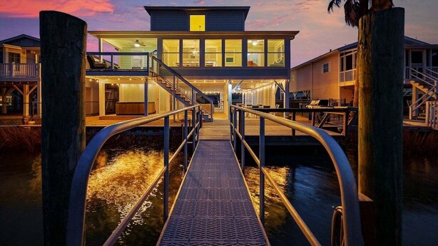 A waterfront property with a covered walkway, a two-story building, and a dock.