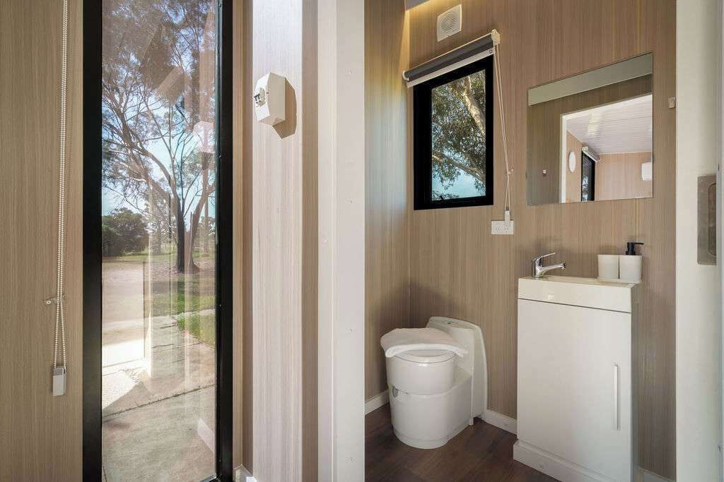 A modern bathroom with a toilet, sink, and mirror.