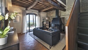 A spacious living room with a modern fireplace, a sofa, and a view through a glass door to the outdoors.