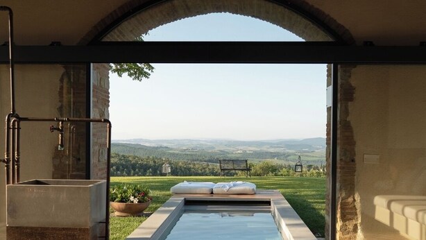 A swimming pool with a view of a landscape, a bench, and a lamp.