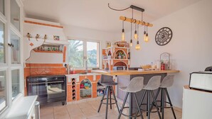 A kitchen with a built-in oven, a brick backsplash, and a bar area with stools.