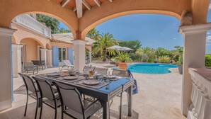 An outdoor dining area with a pool and palm trees.